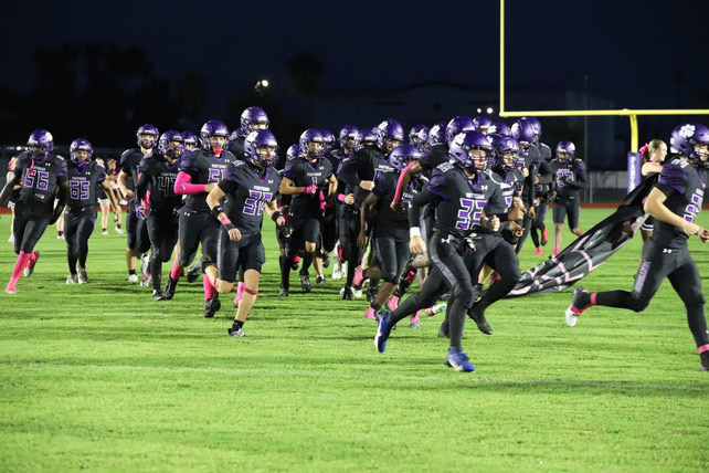 The Panther football team sprints onto the field.